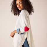 White knit sweater with red heart detail and denim-style accents.
