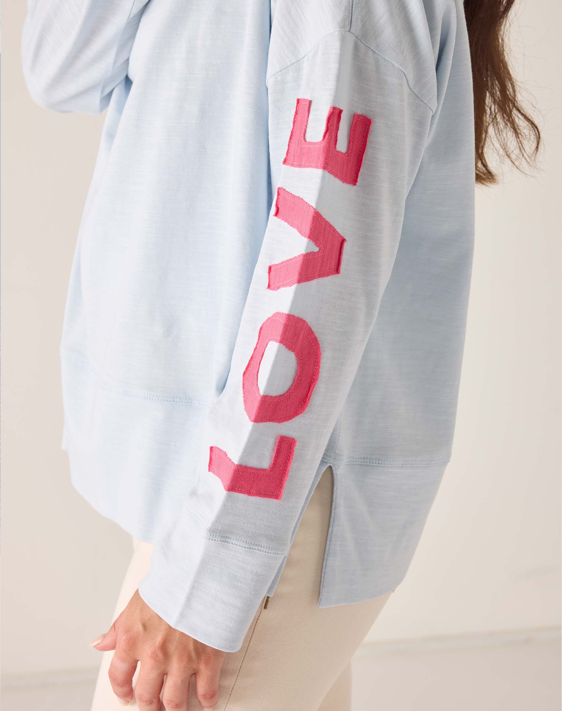 Light blue sweatshirt with pink 'LOVE' text on a plain background