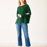 Woman wearing a green sweater with 'LOVE' text and blue jeans on a white background