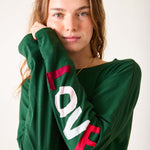 Person wearing a green sweatshirt with 'LOVE' printed on the sleeves against a white background