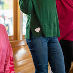 Person wearing a green jacket with a heart design, standing indoors.