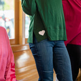 Person wearing a green jacket with a heart design, standing indoors.