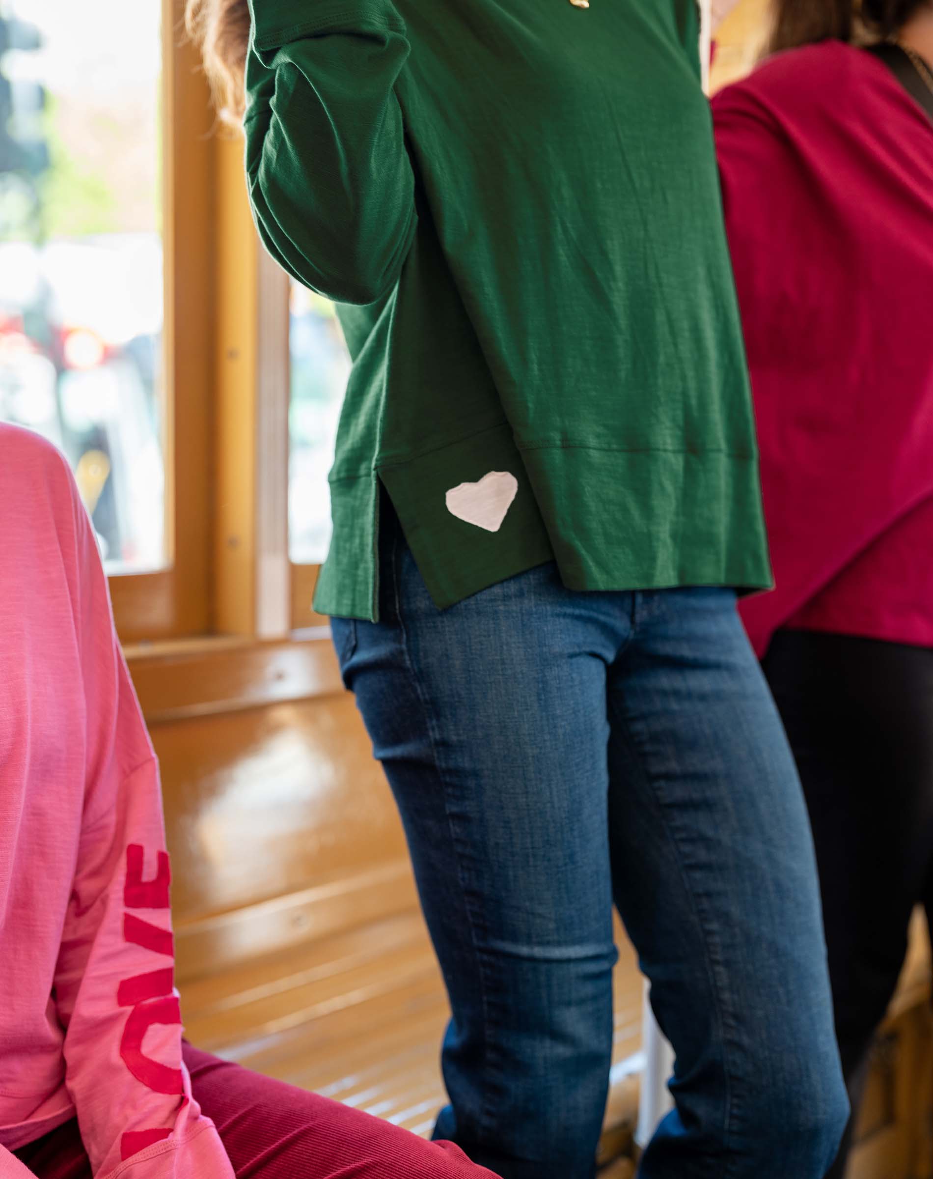 Person wearing a green jacket with a heart design, standing indoors.