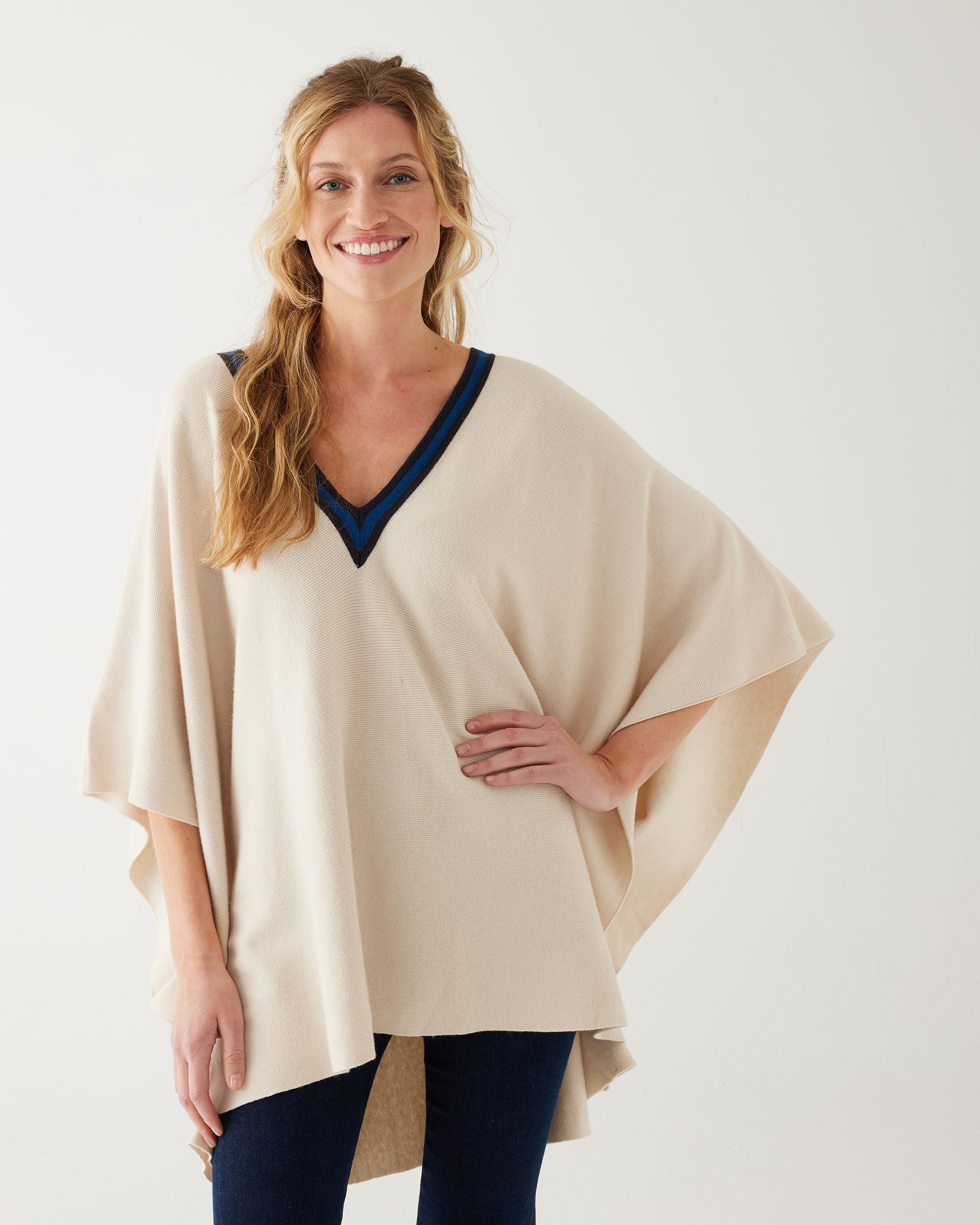 woman wearing mersea Anywear v new poncho in birch beige with blue collar details