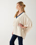 profile of woman wearing mersea Anywear v new poncho in birch beige with blue collar details