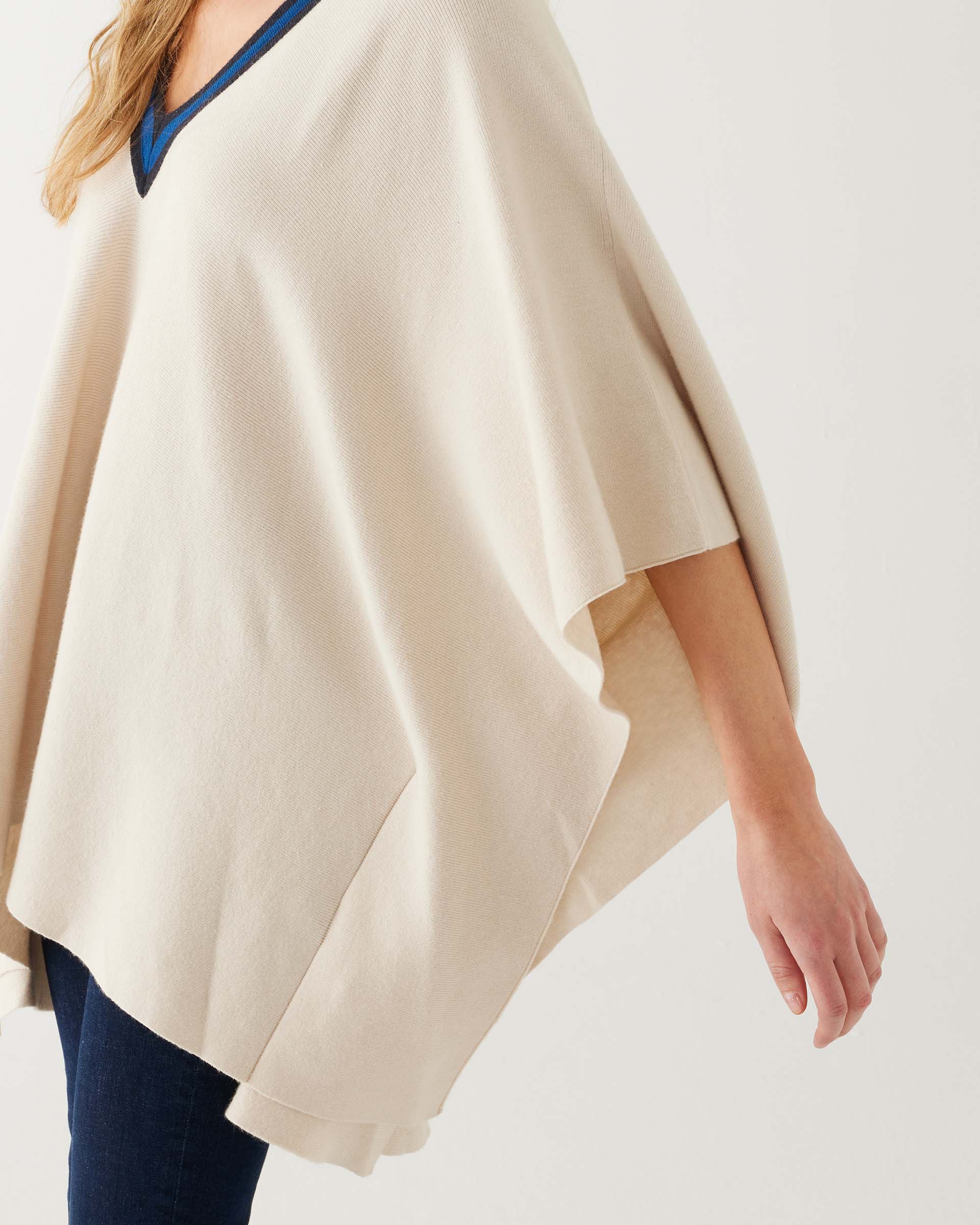 closeup of arm opening on woman wearing mersea Anywear v new poncho in birch beige with blue collar details