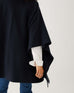 rearview of woman wearing mersea Anywear v new poncho in navy with red and white collar details
