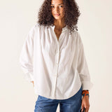Woman wearing a white shirt and blue jeans against a plain background