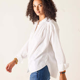 Woman wearing a white blouse and blue jeans against a plain background