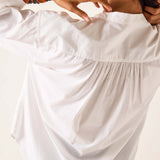 Close-up of a person wearing a white dress with a blurred background