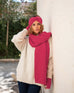 woman wearing mersea rasberry apres scarf headband and fingerless gloves standing against wall