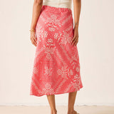 Person wearing a pink patterned skirt on a plain background