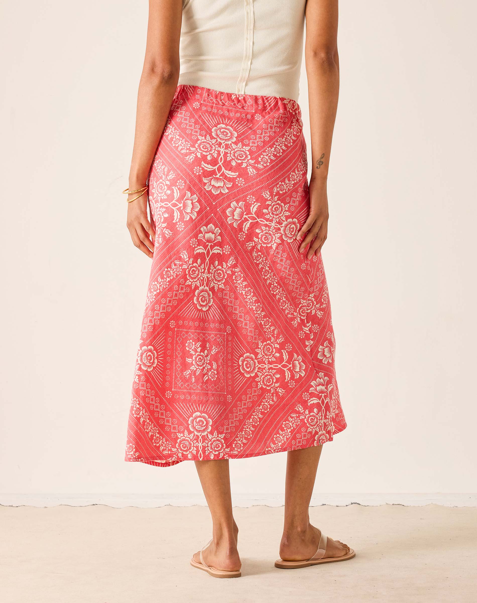 Person wearing a pink patterned skirt on a plain background