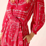 Red dress with white patterns worn by a person on a beige background
