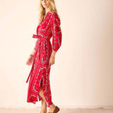 Woman wearing a red patterned dress with a plain background