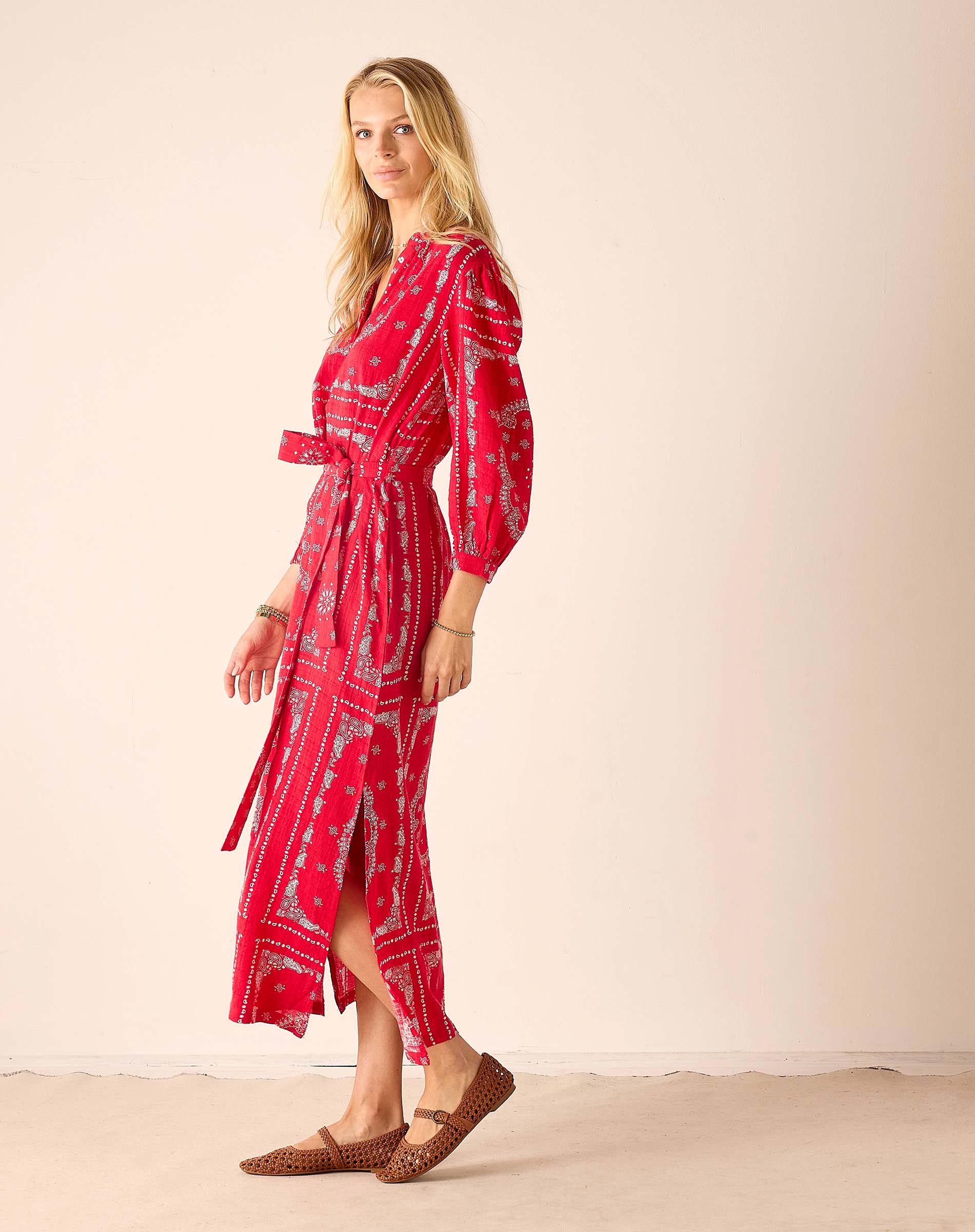 Woman wearing a red patterned dress against a beige background