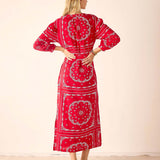 Woman wearing a red patterned dress with a plain background