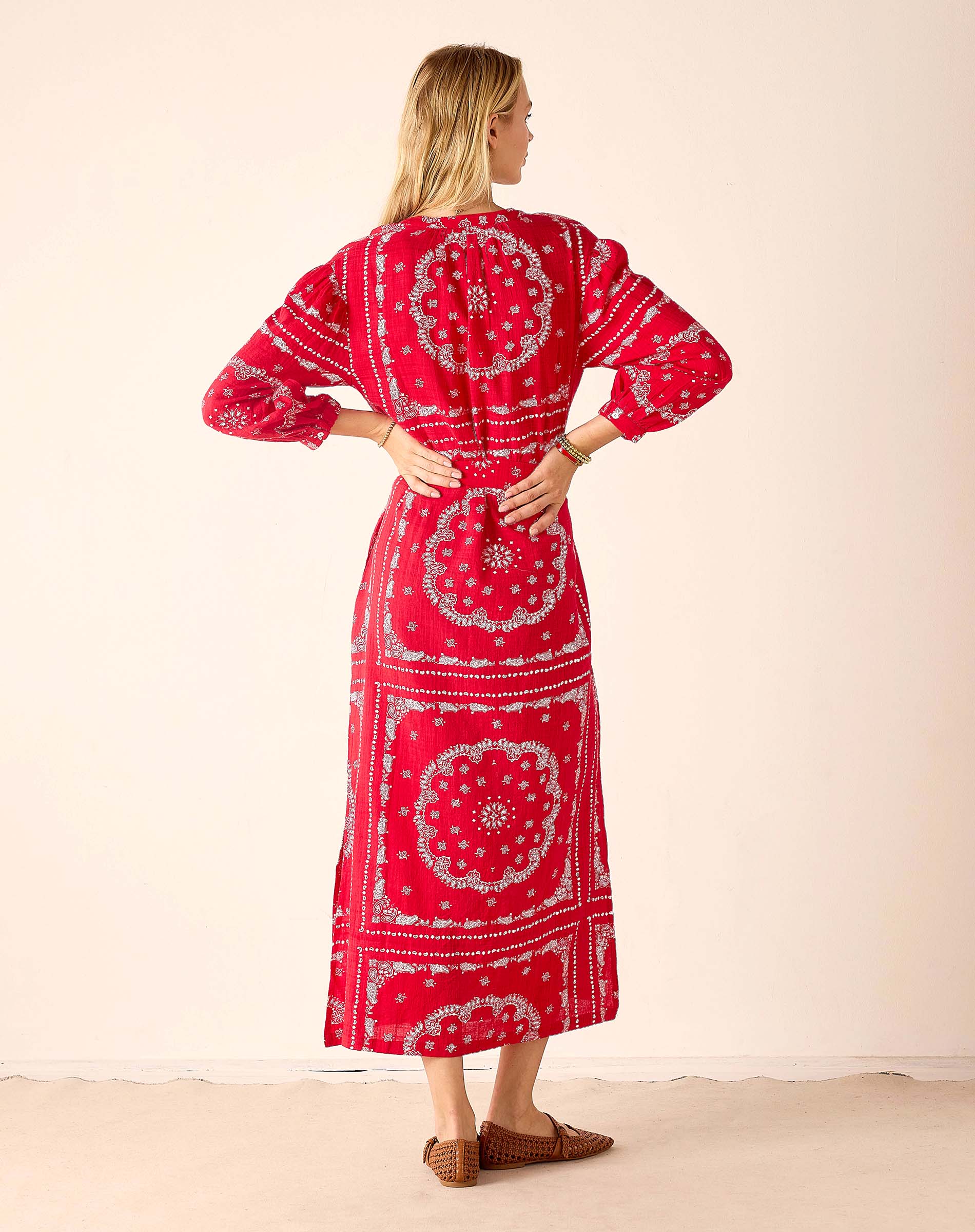 Woman wearing a red patterned dress with a plain background