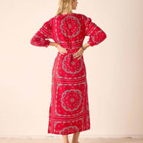Woman wearing a red patterned dress against a beige background