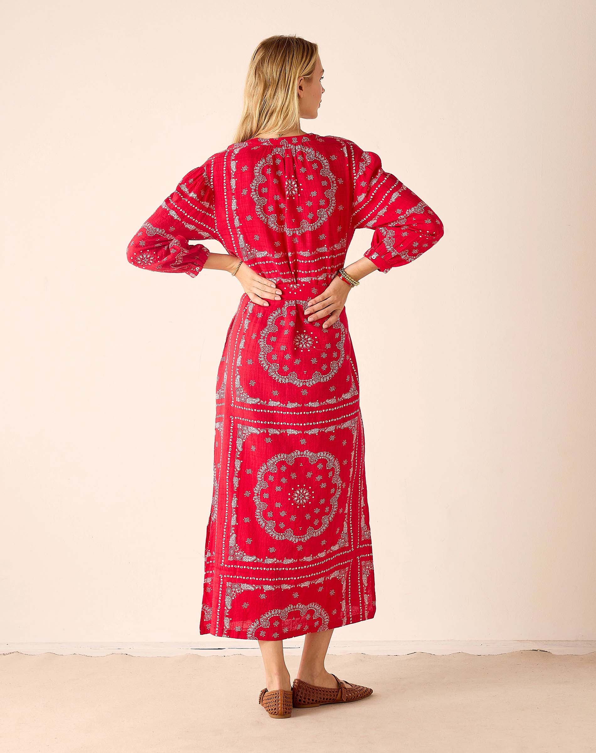 Woman wearing a red patterned dress against a beige background