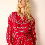 Woman wearing a red patterned dress against a plain background