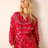 Woman wearing a red patterned dress against a plain background