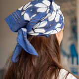 Person wearing a blue and white floral headscarf with a blurred background