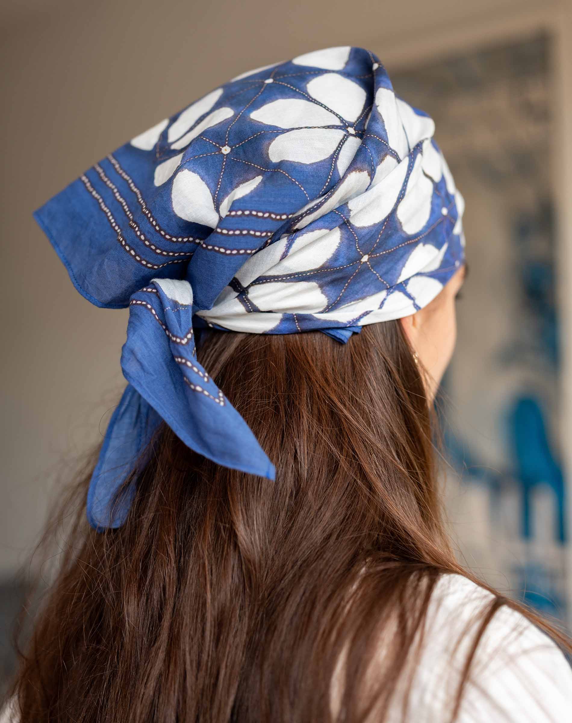 Person wearing a blue and white floral headscarf with a blurred background