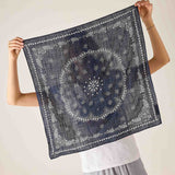 Person holding a dark blue patterned scarf against a plain background