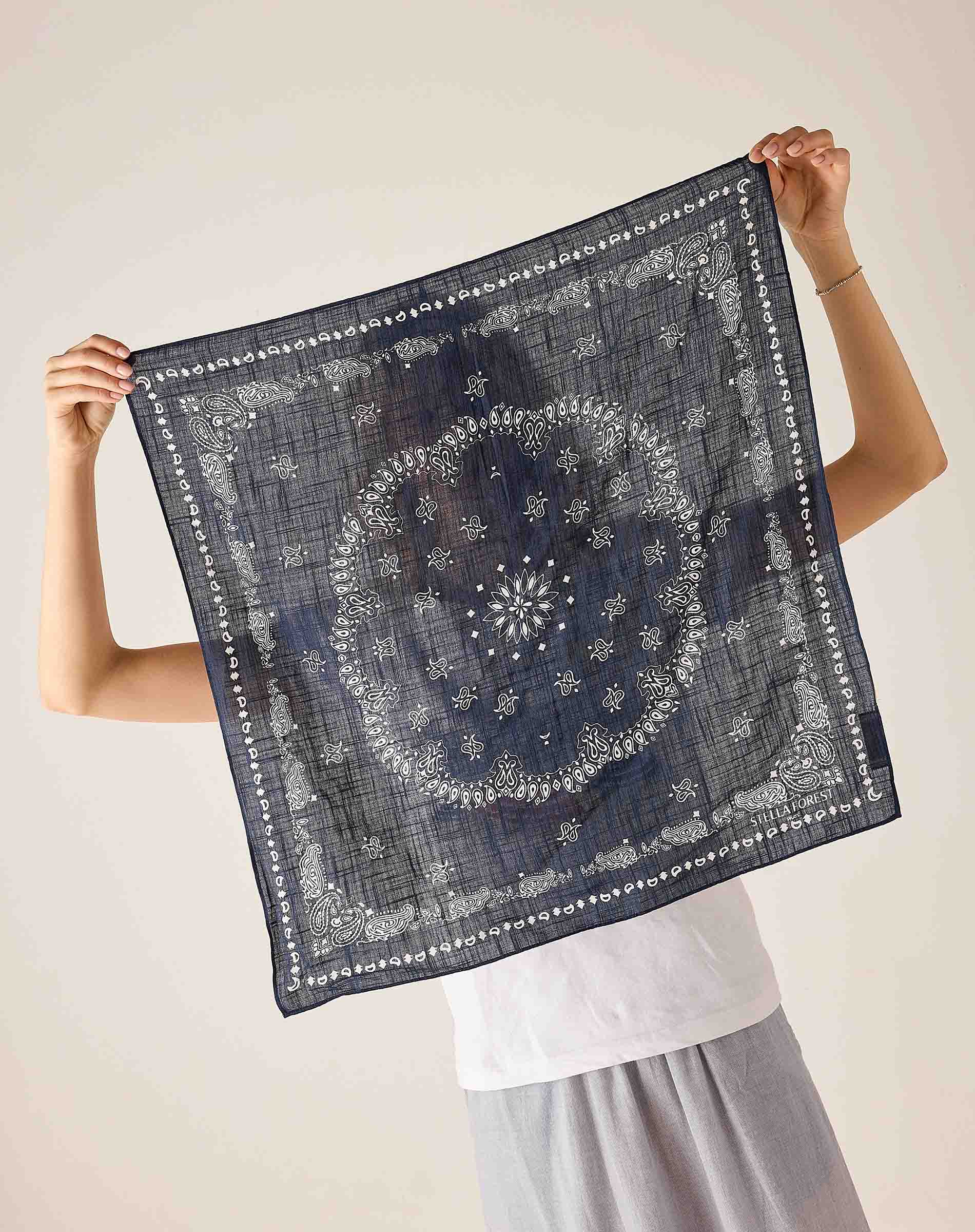 Person holding a dark blue patterned scarf against a plain background
