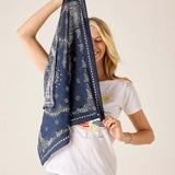 Woman holding a blue patterned scarf against a plain background