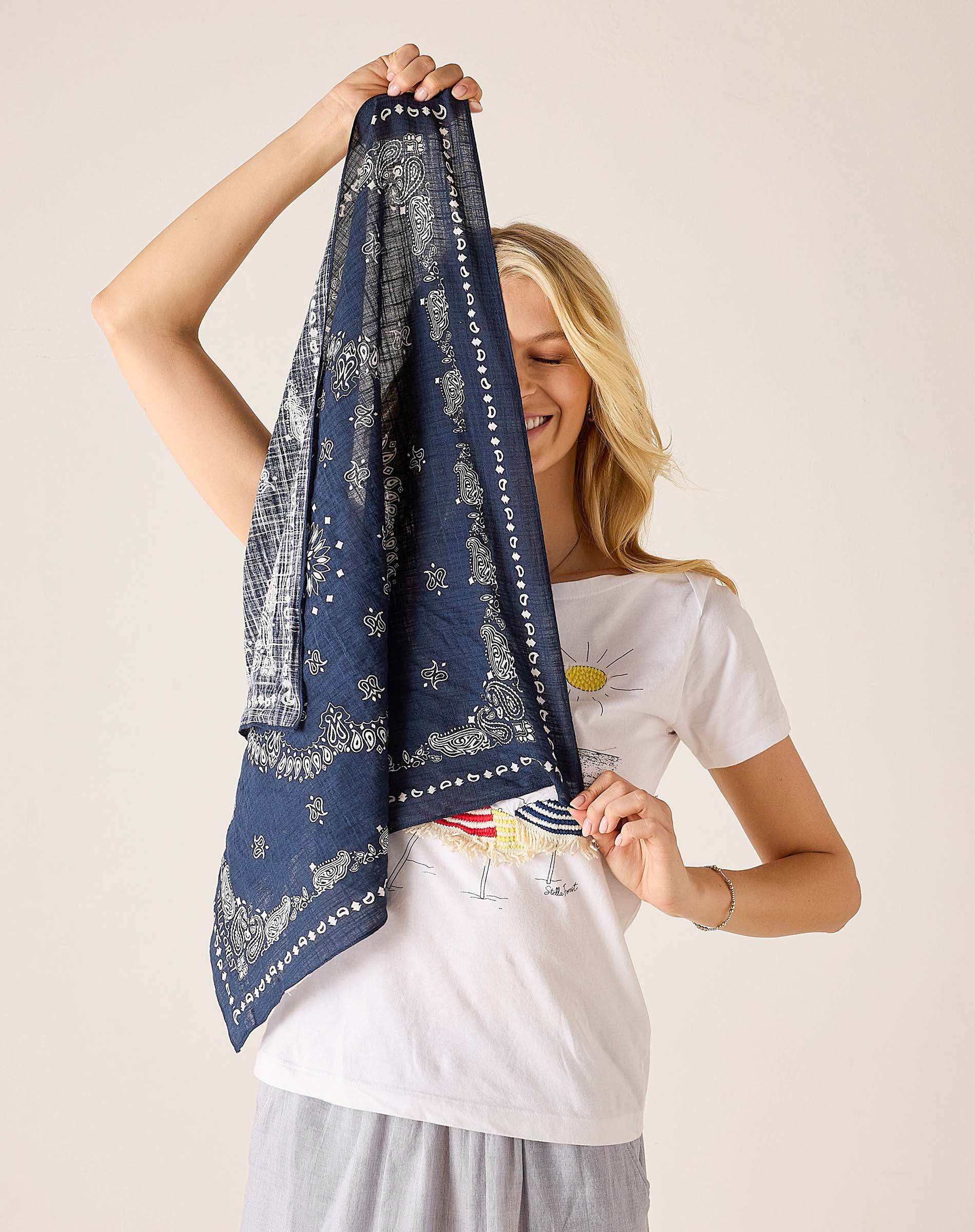 Woman holding a blue patterned scarf against a plain background