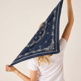 Person holding a navy blue bandana with white patterns against a plain background