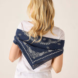 Woman wearing a navy blue bandana with white patterns over her shoulder on a beige background