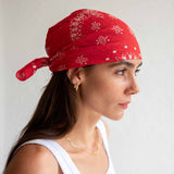 Woman wearing a red bandana with white patterns on a plain background