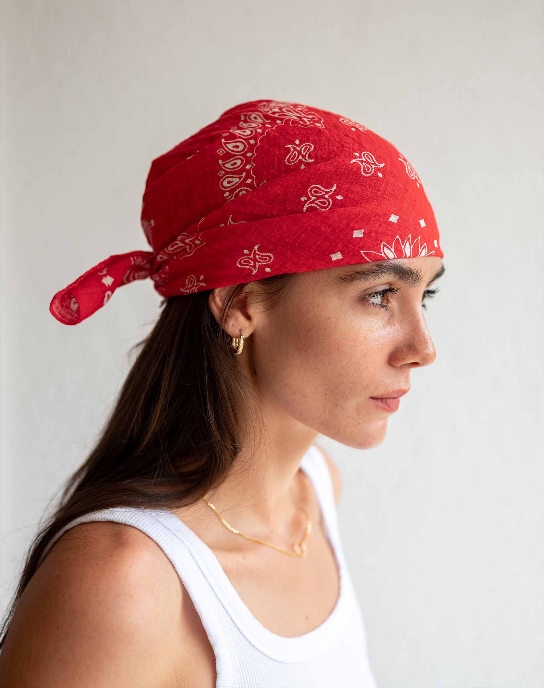 Woman wearing a red bandana with white patterns on a plain background
