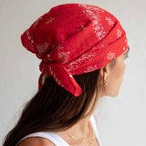 Person wearing a red bandana with white patterns on a plain background