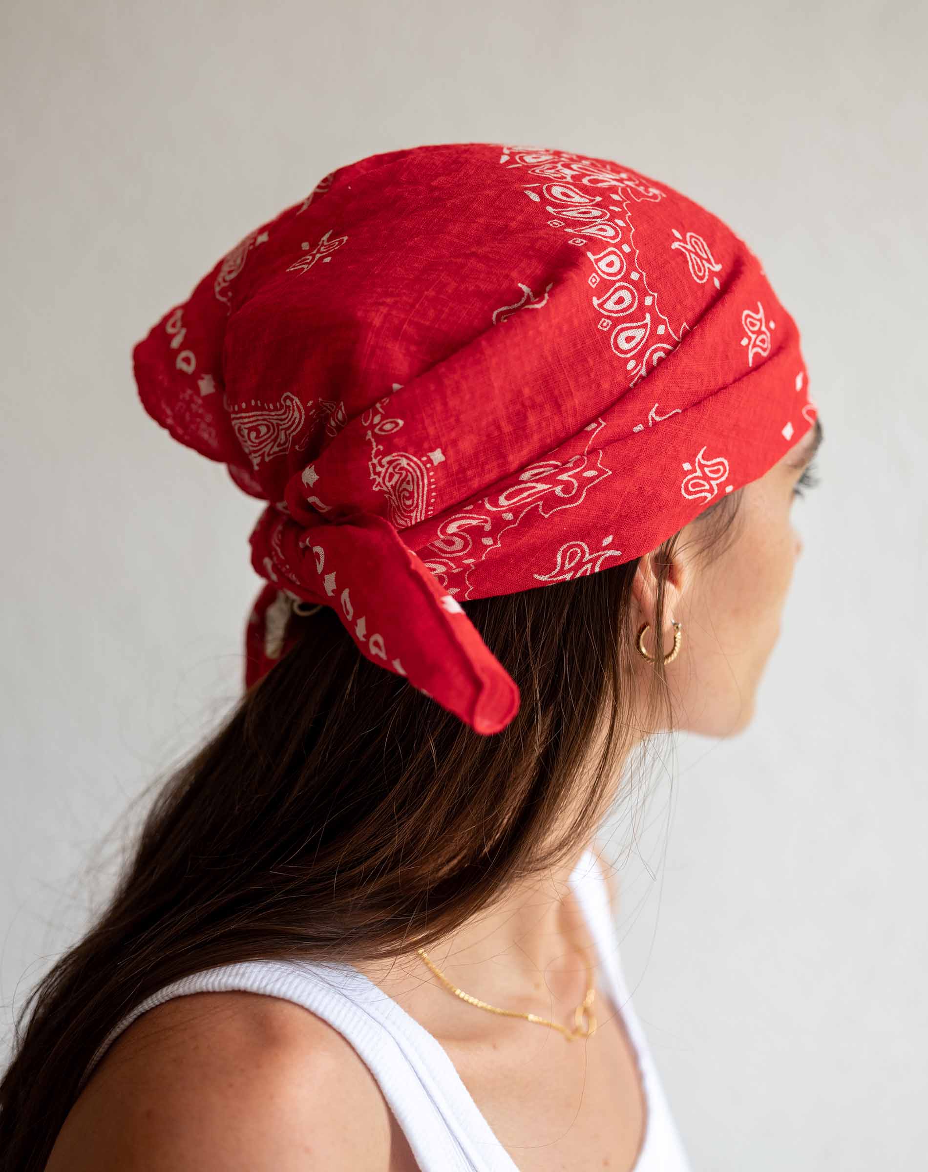 Person wearing a red bandana with white patterns on a plain background