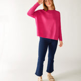 woman wearing mersea banff cashmere sweater in hot magenta standing with right hand near head