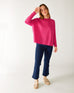 woman wearing mersea banff cashmere sweater in hot magenta standing with right hand near head