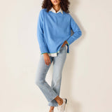 Woman wearing a light blue sweater and jeans against a white background