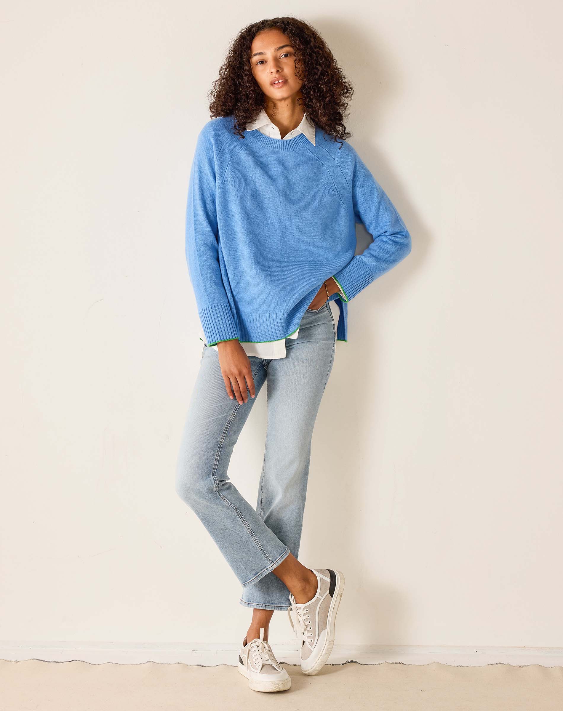 Woman wearing a light blue sweater and jeans against a white background
