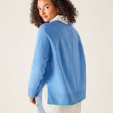 Woman wearing a blue sweater over a white shirt with a beige background