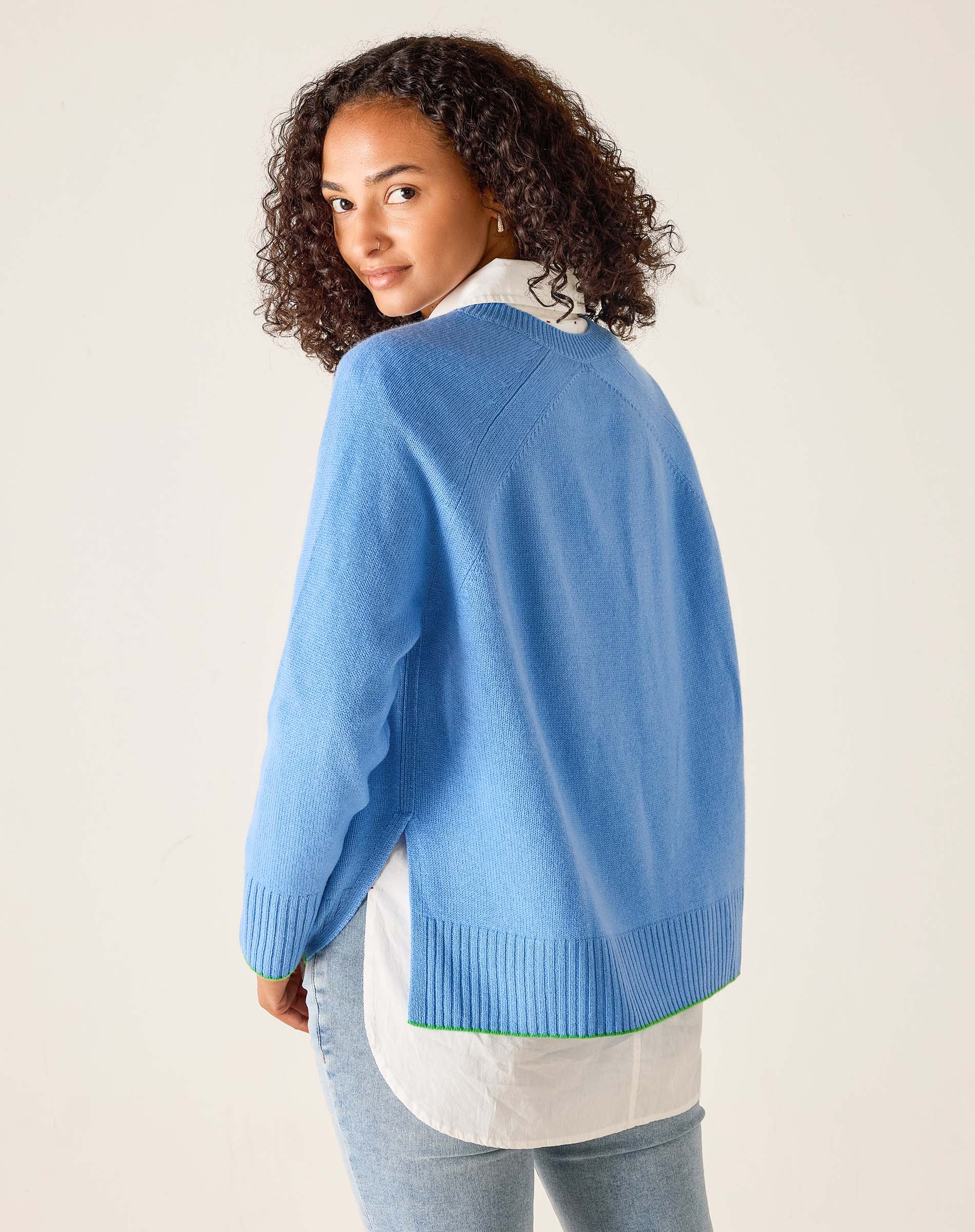 Woman wearing a blue sweater over a white shirt with a beige background