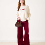 White sweater with red text 'La Rebel' worn by a person on a white background
