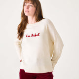 White sweater with red text 'La Rebel' worn by a person on a white background