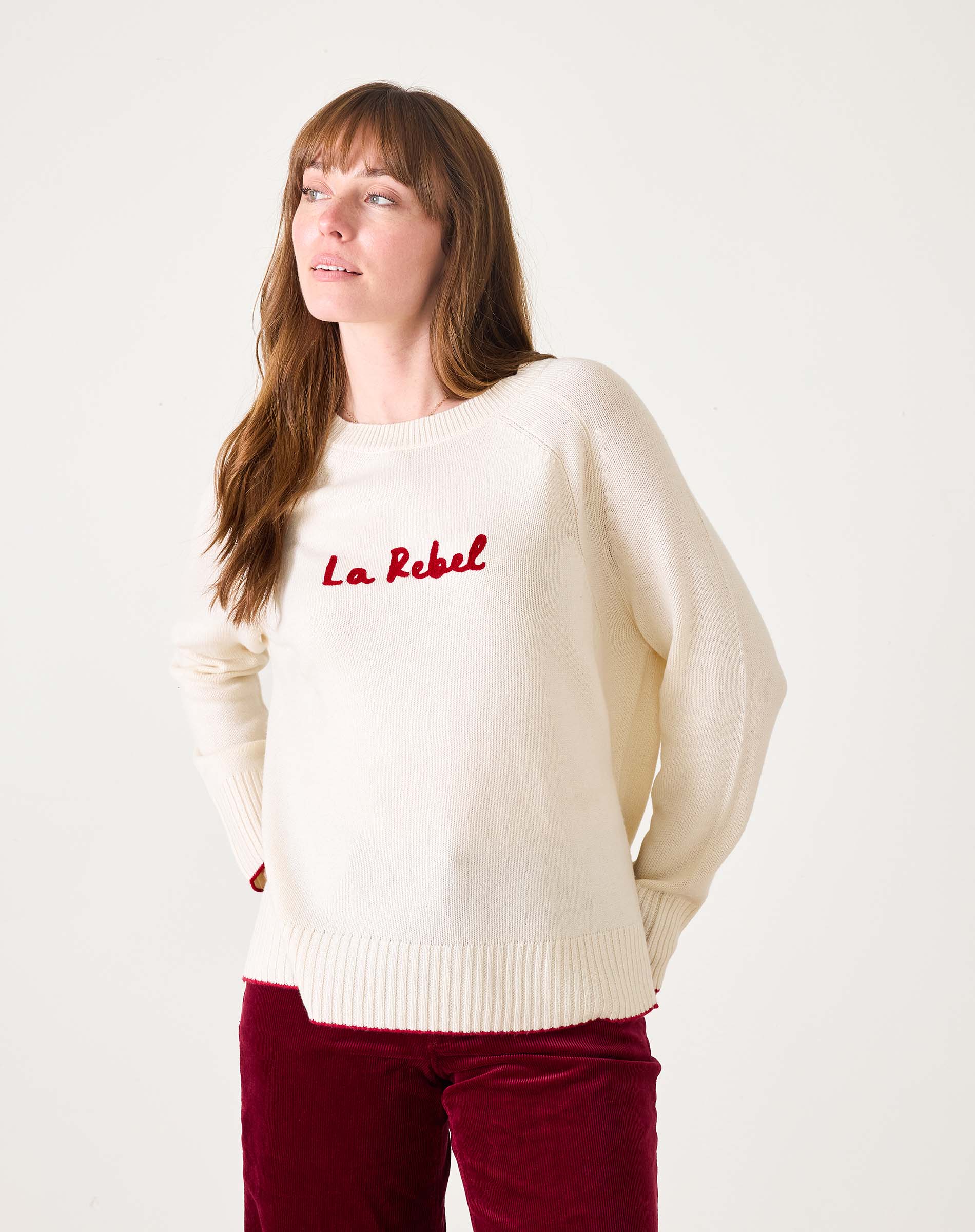 White sweater with red text 'La Rebel' worn by a person on a white background