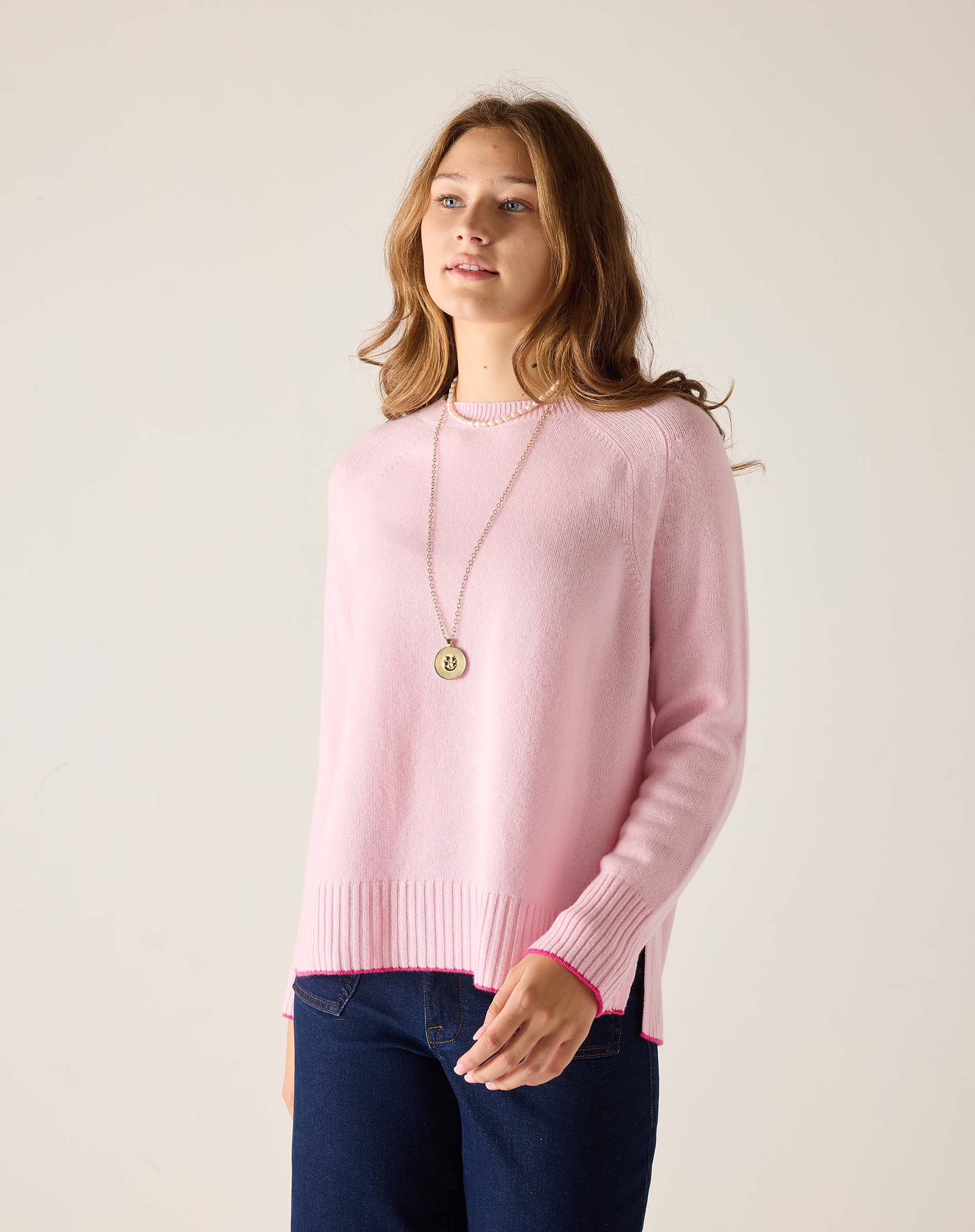 Woman wearing a pink sweater with a plain background