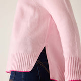 Pink sweater with a subtle pattern worn by a person, on a plain background
