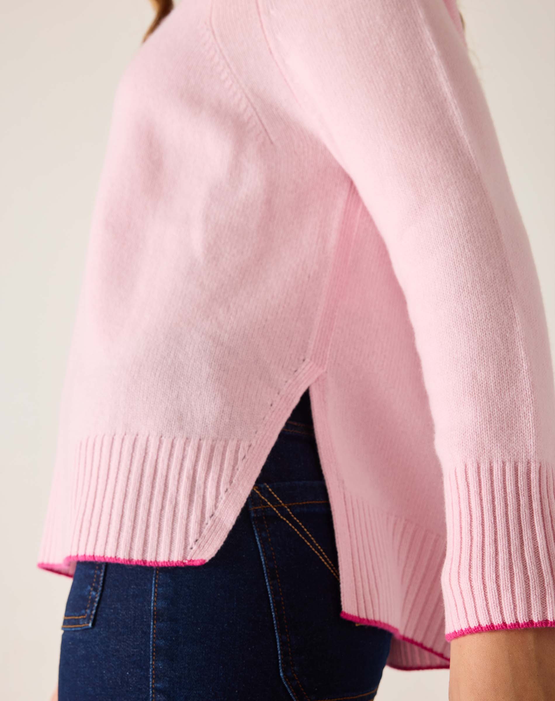 Pink sweater with a subtle pattern worn by a person, on a plain background